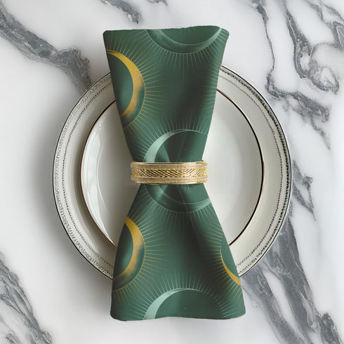 Four-piece cloth napkin set featuring a celestial print of radiant golden crescent moons and pale sunburst orbs against a rich emerald green background. Each napkin displays symmetrical, glowing motifs inspired by lunar phases and cosmic geometry. The fabric is neatly folded to showcase the repeating pattern, with a soft matte finish and fine detailing, perfect for mystical or magical table settings, altar decor, or celestial-inspired dining aesthetics.